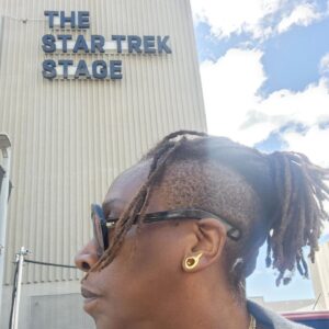 Gina Yashere Instagram - New journey, new TV family ... Yup, that is Holly Hunter & Paul Giammatti standing behind me. This lil girl from Bethnal Green, East London, is now acting opposite these GIANTS. 🤣
Today marks the official start of production on #starfleetacademy
on @startrekonpplus.
I'm excited for this! LET'S 'AVE IT CADETS! 🖖🏿🖖🏿 #livelongandprosper

#StarTrek Stage welcomes #StarfleetAcademy.
#ginabackinhollywood #comedian #showrunner #writer #actor