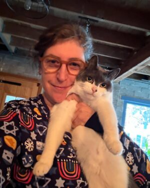 Mayim Bialik Instagram - These Little Sleepies Chanukah PJs are so incredibly soft that I thought my softest cat would love posing with me in them—we’d feel like we were one. 🤦‍♂️ Spoiler: She did not enjoy the photo shoot, but the pajamas are just as cozy and soft as Addie! @littlesleepies