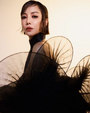 Fiona Xie Instagram - The Alchemy of @irisvanherpen @voguesingapore 

“I find beauty in the continual shaping of chaos which embodies the primordial power of nature’s performance,” Iris van Herpen once said—words that illuminated my understanding of her work at the nexus of ancient alchemy and @cern physics.

Her liminality is her genius. “I see technology as a tool to express the handwork better,” she explains, dissolving false binaries. When her kinetic structures breathe with the wearer, we witness her core philosophy: “Movement is my constant inspiration. Our human body is in continuous motion, as is everything around us.”

These undulating architectures manifest what philosopher Merleau-Ponty called “the flesh of the world”—the profound interconnectedness between perceiver and perceived. Her approach transforms rigid materials into liquid motion, embodying Bachelard’s insight that “matter is the unconsciousness of form.”

I remember showing my friend @grimes in that “Dune of Souls” creation at the met gala whispering “It would be a dream to wear these.” Then @voguesingapore @nat_tasha ‘s call came—Iris would dress me for the @artsciencemuseumsg retrospective. I swooned like a teenager locked lips in her first kiss. Manifestation is real. 

“Fashion is an expression of the zeitgeist, while couture is an expression of eternal beauty.” These words resonated as I stood transfixed clad in her “Architectonics” collection—embodying what Rilke meant by “living the questions” about our relationship with technology, philosophy, architecture, music, nature, and our bodies.

Draped in her vision, I understood: Iris van Herpen doesn’t design clothing. She designs portals to possibility itself.​​​​​​​​​​​​​​​​

Be transcended at @artsciencemuseumsg 
#IrisVanHerpen #ArtAndFashion #Metamorphosis​​​​​​​​​​​​​​​​ #Vogue